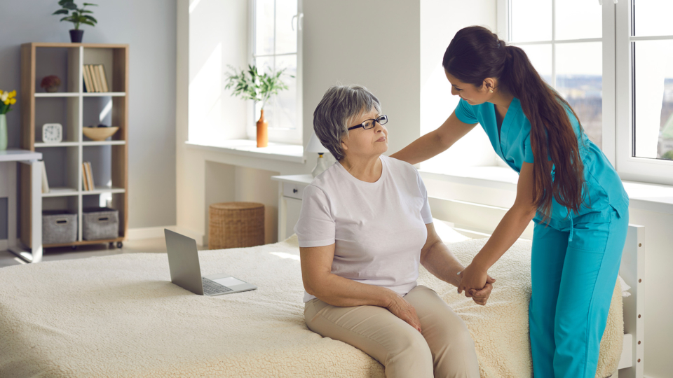 Caretaker Holding Hand Of A Resident In Assisted Living Room