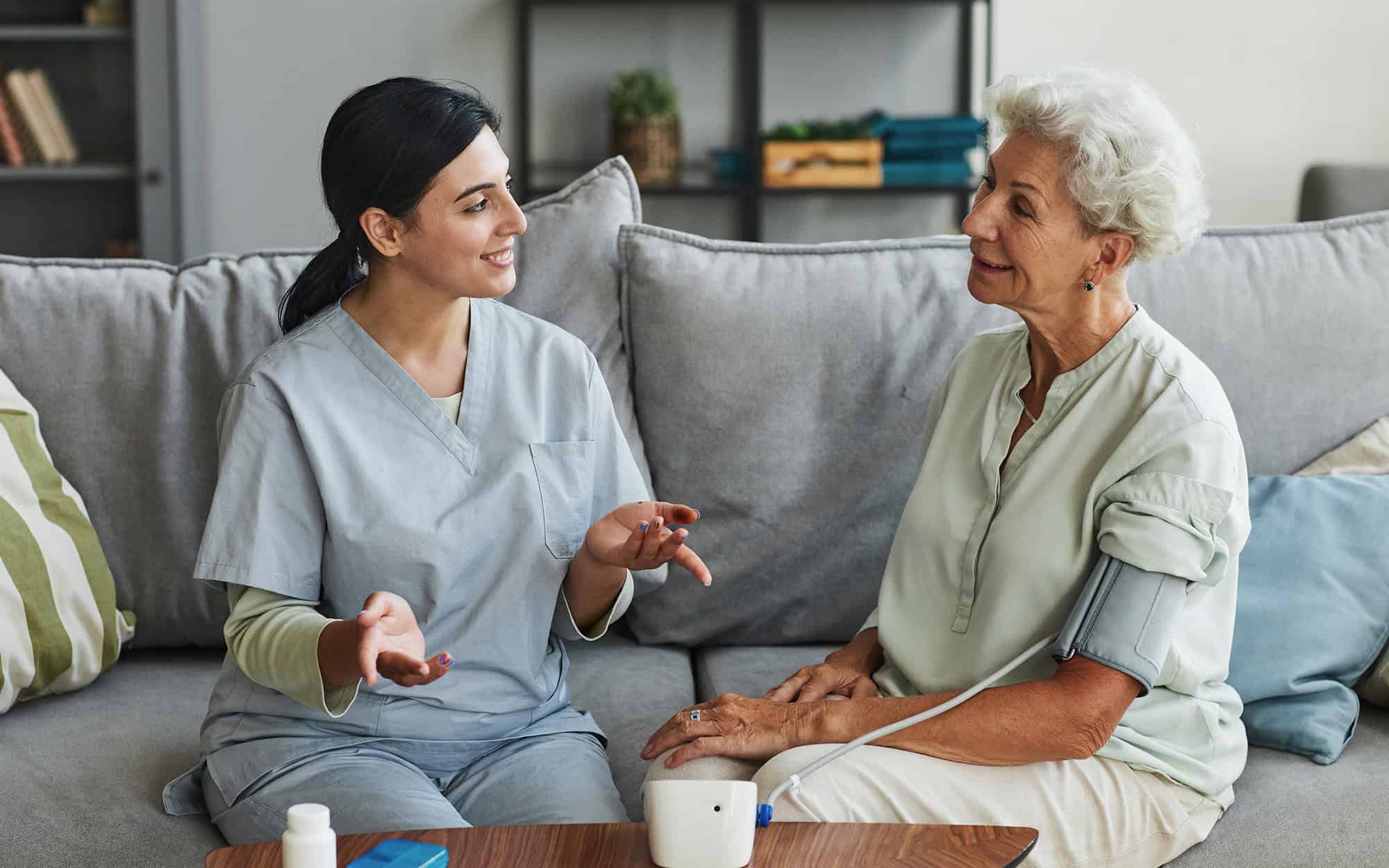 Nurse Taking Blood Pressure Of Resident On Couch