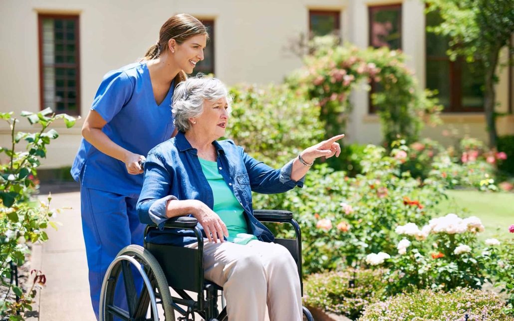 Shot Of A Resident And A Nurse Outside In The Retirement Home Garden