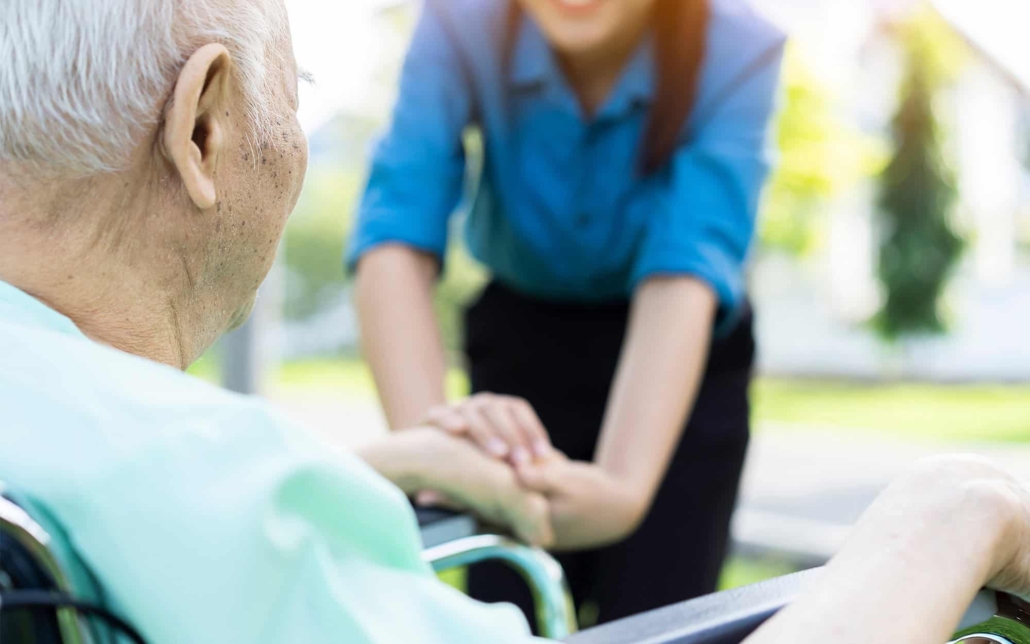 Side view of a caregiver holding elderly patient's hand