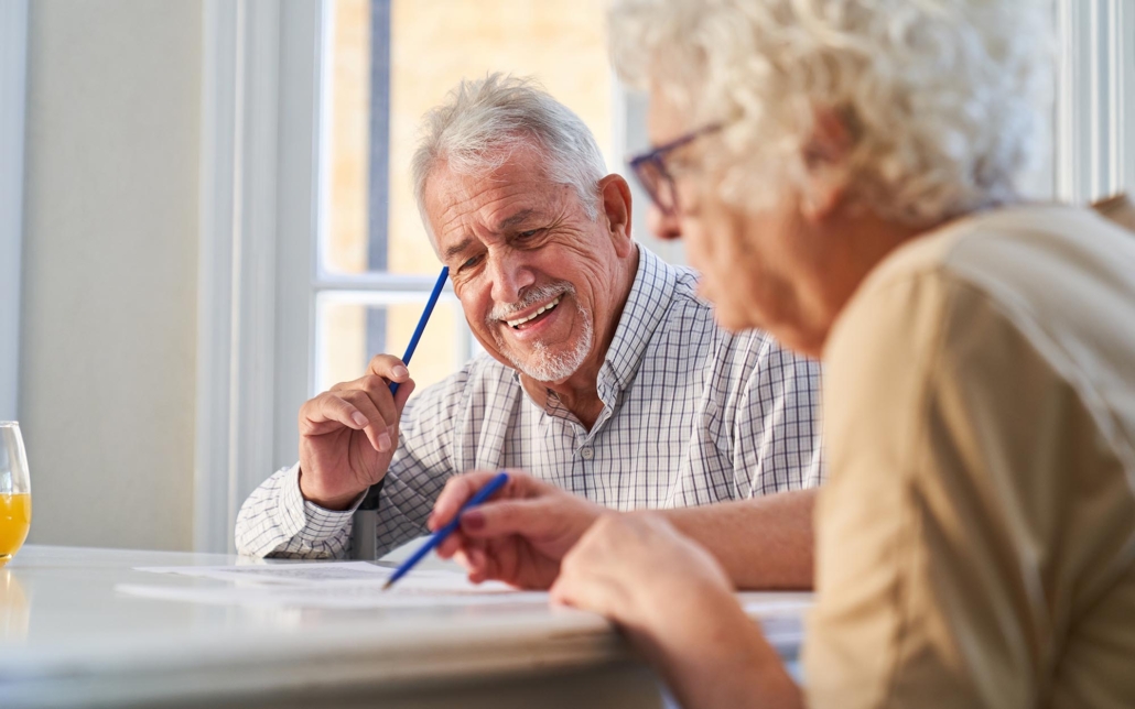 Two Elderly Adults Playing Word Games At Table