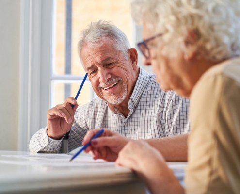 Two Elderly Adults Playing Word Games At Table