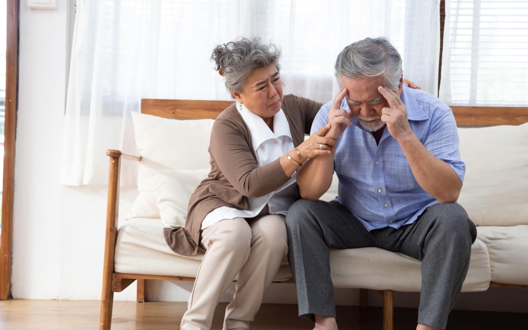 Elderly Couple Sitting On Couch Struggling To Remember Something