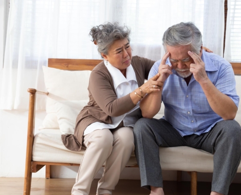 Elderly Couple Sitting On Couch Struggling To Remember Something