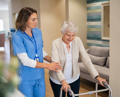 Nurse Helping Senior Woman To Walk At Private Clinic