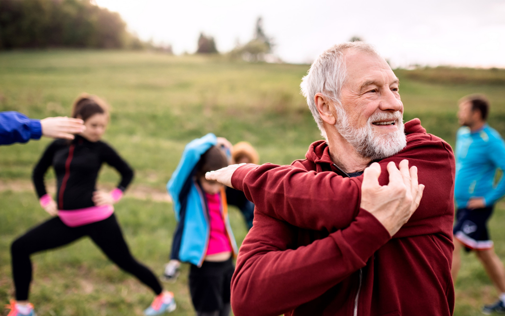 Large Group Of Fit And Active People Doing Exercise In Nature, Stretching