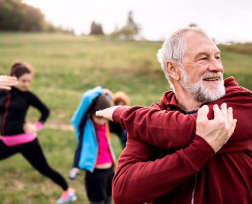 Large Group Of Fit And Active People Doing Exercise In Nature, Stretching